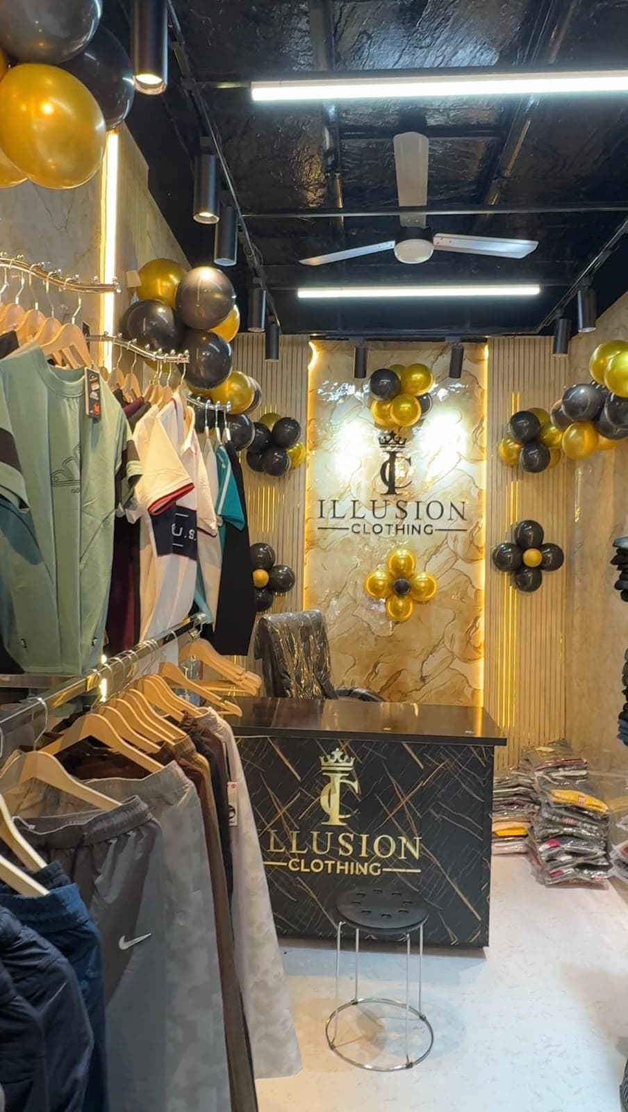 Illusion Clothing counter with gold logo and clothing racks